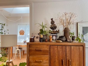 A wooden cabinet with drawers, a desk with a lamp, and various potted plants. - Artist’s EcoRetreat in the heart of Ballard (Seattle)