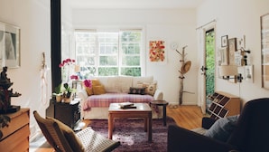A cozy living room with a sofa, a coffee table, and a fireplace. - Artist’s EcoRetreat in the heart of Ballard (Seattle)