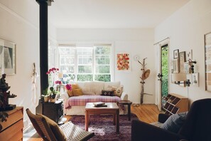 A cozy living room with a sofa, a coffee table, and a fireplace. - Artist’s EcoRetreat in the heart of Ballard (Seattle)