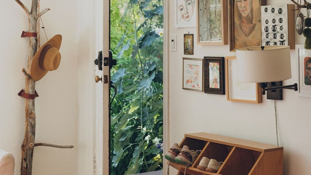 A room with a wooden floor, a door leading to a garden, a wall-mounted shoe rack, and various framed artworks. - Artist’s EcoRetreat in the heart of Ballard (Seattle)