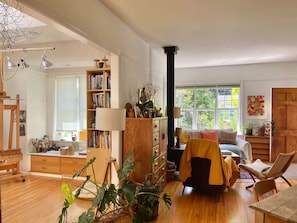 A spacious living room with a fireplace, a bookshelf, a sofa, and a dining area. - Artist’s EcoRetreat in the heart of Ballard (Seattle)