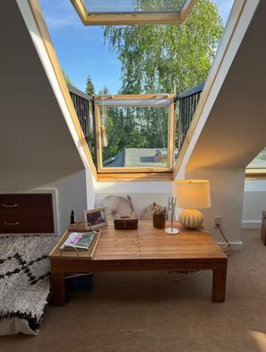 A loft bedroom with a skylight, wooden furniture, a lamp, and a view of trees. - Artist’s EcoRetreat in the heart of Ballard (Seattle)