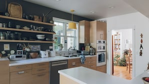 A modern kitchen with wooden cabinets, a dishwasher, and a large window. - Artist’s EcoRetreat in the heart of Ballard (Seattle)