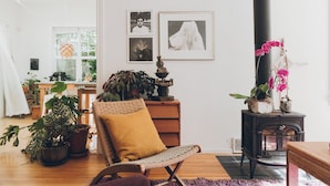 A cozy living room with a wicker chair, a small table with a statue, and a potted plant. - Artist’s EcoRetreat in the heart of Ballard (Seattle)