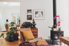 A cozy living room with a wicker chair, a small table with a statue, and a potted plant. - Artist’s EcoRetreat in the heart of Ballard (Seattle)