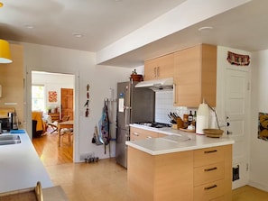 A modern kitchen with wooden cabinets, a stainless steel refrigerator, and a white countertop. - Artist’s EcoRetreat in the heart of Ballard (Seattle)