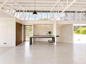 A spacious, modern interior with a large, open kitchen area, a wooden door, and a view of greenery outside. - Modern Apartment on a High Floor in Santa Tecla (Santa Tecla)