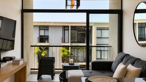 A modern living room with a sofa, a TV, and a balcony with plants. - Santa Tecla | Modern high-floor apartment (Santa Tecla)