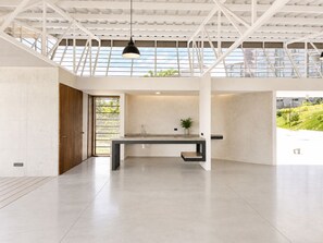 Ein großzügiges, modernes Interieur mit einer geräumigen, offenen Küche, einer Holztür und Blick ins Grüne.