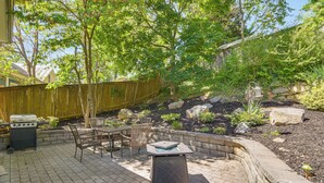 Een terras met een barbecue, tuinmeubilair en een stenen muur.