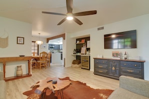 A spacious living area with a dining table, chairs, a sofa, a coffee table, a fireplace, a ceiling fan, a TV, and a kitchen in the background. - 4 Mi to Old Town! Extended Desert Escape w/ Pool (Phoenix)