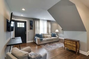 A living room with a sofa, a coffee table, a TV, and a wooden dresser. - Spacious 4-bedroom house in adorable Hendersonville with AC (Hendersonville)