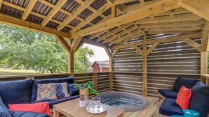 Un patio exterior con terraza de madera, un jacuzzi y dos sofás con cojines.