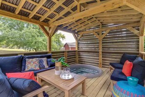 An outdoor patio with a wooden deck, a hot tub, and two sofas with cushions. - Spacious 4-bedroom house in adorable Hendersonville with AC (Hendersonville)