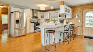 Een moderne keuken met roestvrijstalen apparatuur, houten vloeren en een centraal eiland met barstoelen.