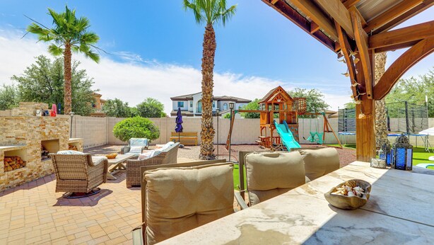 An outdoor patio with wicker furniture, a palm tree, and a play structure. - Pool, Hot Tub, Toys! Family Home, 4 Mi to Luke AFB (Litchfield Park)