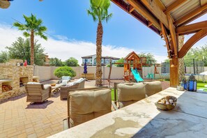 An outdoor patio with wicker furniture, a palm tree, and a play structure. - Pool, Hot Tub, Toys! Family Home, 4 Mi to Luke AFB (Litchfield Park)