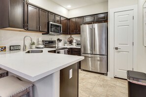 A kitchen with dark wood cabinets, stainless steel appliances, a white countertop, and a built-in oven. - Community Perks! Modern PHX Condo: Extended Stay! (Phoenix)