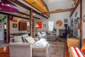 A cozy living room with a fireplace, a couch, a coffee table, and a surfboard.