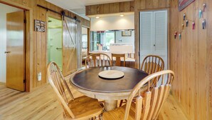 A wooden interior with a round dining table, wooden chairs, a kitchen area, and a sign that reads 'Good times come to those who bait.' - Lake Webster Retreat: Pier, Kayaks & Fire Pit (North Webster)