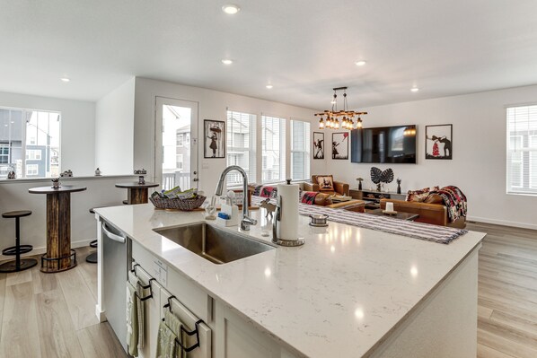 A spacious kitchen with a large island, modern appliances, and a dining area with a sofa and TV. - Pets Welcome! Thornton Extended Stay w/ Balcony (Thornton)
