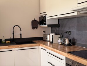 Eine moderne Küche mit Schwarz-Weiß-Farbgestaltung, ausgestattet mit Spüle, Mikrowelle, Wasserkocher und Toaster.
