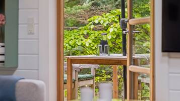 Une table en bois avec un plateau en verre, une chaise et une vue sur la verdure à l’extérieur.