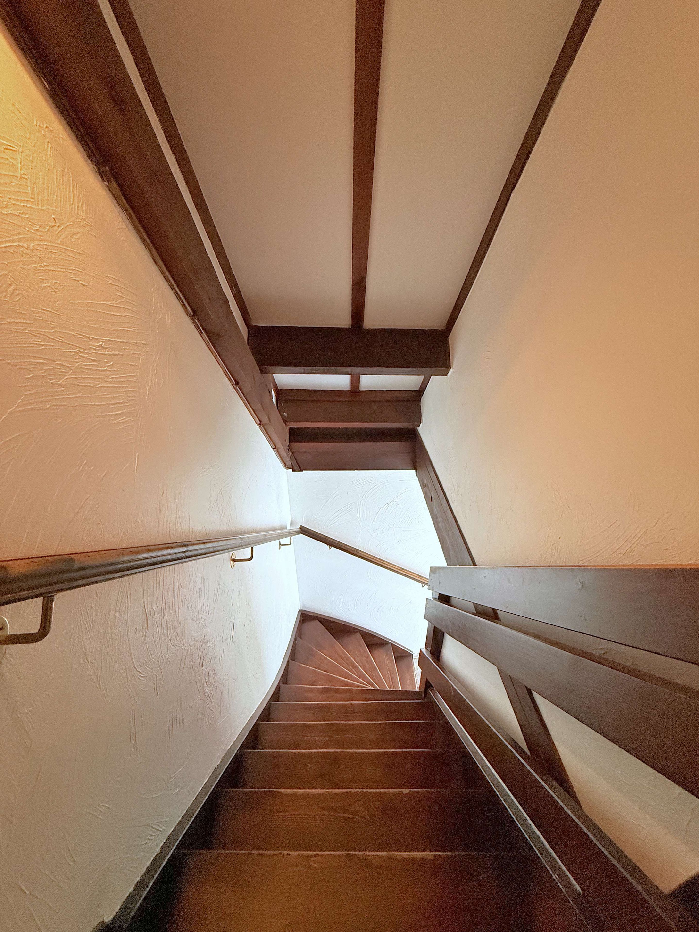 A spiral staircase with wooden handrails and a white wall.