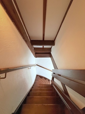 A spiral staircase with wooden handrails and a white wall.