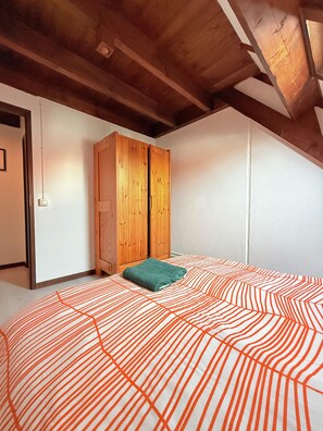 Une chambre à coucher avec un lit, une armoire en bois et un mur blanc.
