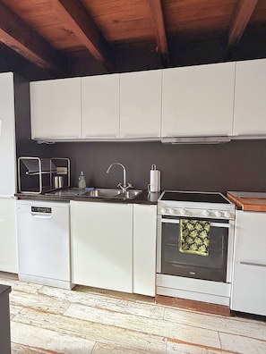 A kitchen with white cabinets, a dishwasher, a sink, a stove, and a wooden ceiling.