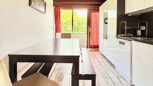 A kitchen with a wooden table and bench, white cabinets, and a view through a window.