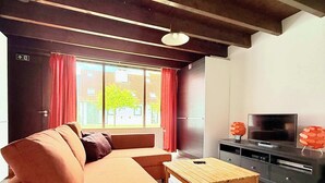 A modern living room with a sofa, a wooden coffee table, a TV, and a cabinet.