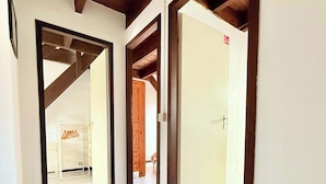 A hallway with wooden beams, white walls, and a door leading to another room.