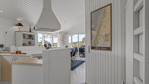 Eine moderne Küche mit weißen Schränken, einer großen Kochinsel und einem Essbereich mit Stühlen.