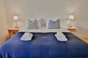 A bed with two pillows, two bedside lamps, and two folded towels. - Limehouse Eco Guesthouse (Slane)
