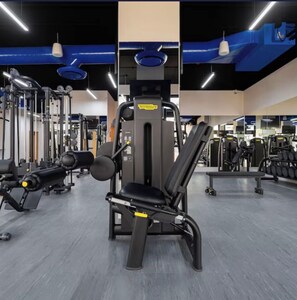 Une salle de sport équipée de divers appareils d’exercice, d’un banc de développé couché et d’un support à squats.