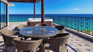A covered outdoor seating area with a hot tub, wicker furniture, and a view of the ocean. - Luxury Cabo Escapes Suites, Villas & Elevated Experiences by Chez Tandrie (San José del Cabo)