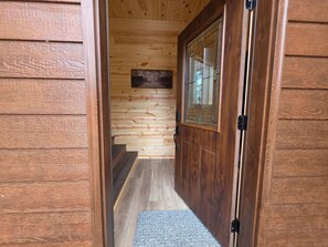 A wooden interior with a door, a staircase, and a small rug.