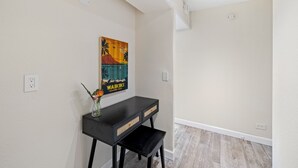 Una habitación con una consola negra, un cuadro y un florero con flores.