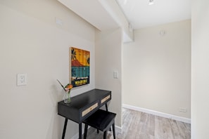 A room with a black console table, a painting, and a vase with flowers. - Renovated 2BR/2BA in Waikiki Walk to Beach (Honolulu)