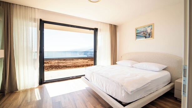 Een slaapkamer met een groot bed, uitzicht op het strand en een schilderij aan de muur.