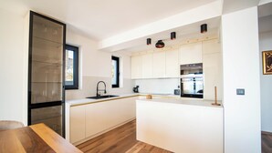 Een moderne keuken met witte kastjes, een houten eettafel en een vast kookeiland.
