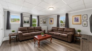 A living room with two brown leather sofas, a wooden coffee table, and a television on a wooden stand. - The Grandstands Apt 2 - All Star Baseball Rentals (Oneonta)