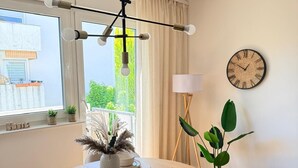 Un comedor con una mesa redonda, sillas, un reloj de pared y un ventanal con cortinas.