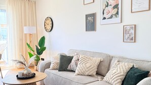 Una sala de estar con sofá, una mesa de centro, una lámpara e impresiones enmarcadas de motivos botánicos en la pared.