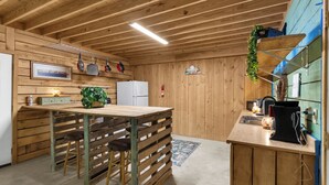 A wooden interior with a kitchen area featuring a refrigerator, a sink, and a stove.