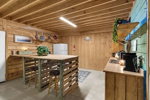 Un interior de madera con una zona de cocina que incluye un refrigerador, un lavamanos y una estufa.