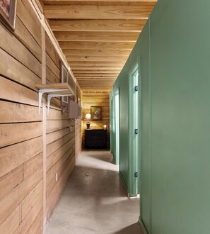 Un pasillo estrecho con paredes de madera y una puerta verde.