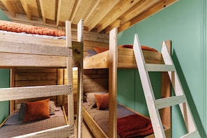 Cama litera con escalera, paredes de madera y pared verde.